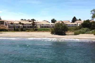 a view of a beach with buildings in the background at Studio 2 personnes vue mer et pieds dans l'eau in Linguizzetta