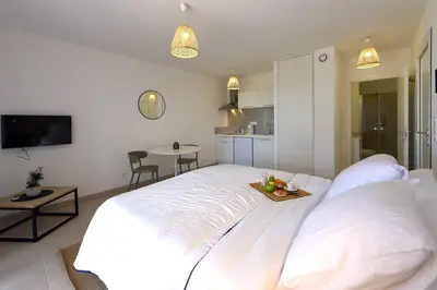 a large white bed in a room with a kitchen at Studio 2 personnes vue mer et pieds dans l'eau in Linguizzetta