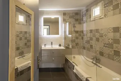 a bathroom with a tub and a sink and a mirror at Résidence CasaBianca Porticcio - Nino in Grosseto-Prugna