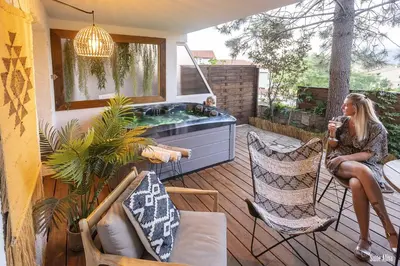 a woman sitting in a chair on a deck with a hot tub at Résidence CasaBianca Porticcio - Aliva in Porticcio