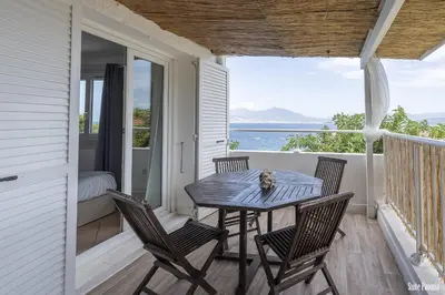 a table and chairs on a porch with a view of the ocean at Résidence CasaBianca Porticcio - Paomia in Porticcio
