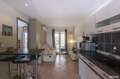 a kitchen with a counter top and a living room at Résidence CasaBianca Porticcio - Paomia in Porticcio