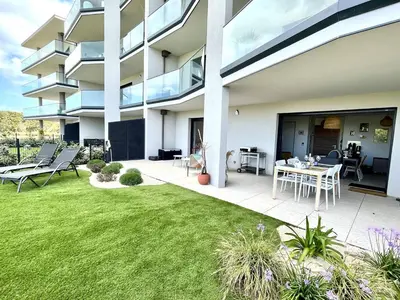 a large building with a patio with a grass yard at Appartement jardin de livia 2 rez de jardin in Porticcio