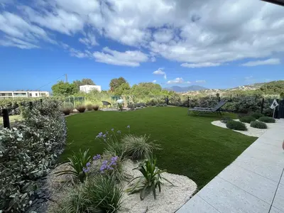a garden with a bench and a green lawn at Appartement jardin de livia 2 rez de jardin in Porticcio