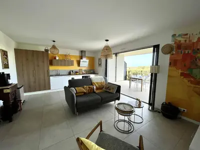 a living room with a couch and a kitchen at Appartement jardin de livia 2 rez de jardin in Porticcio