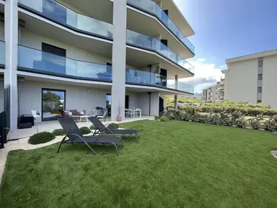 a large building with two chairs and a lawn at Appartement jardin de livia 2 rez de jardin in Porticcio