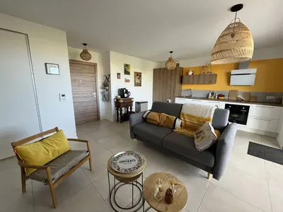 a living room with a couch and a kitchen at Appartement jardin de livia 2 rez de jardin in Porticcio