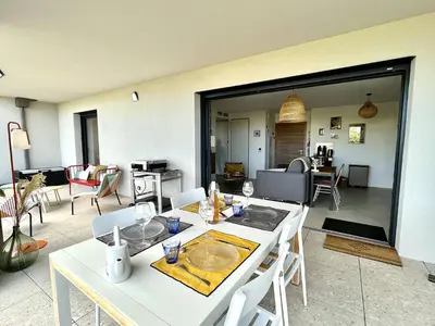a white table and chairs in a living room at Appartement jardin de livia 2 rez de jardin in Porticcio