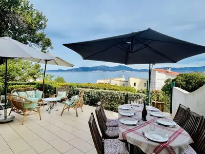 a table with chairs and an umbrella on a patio at Maison 4 pièces PIETROSELLA in Pietrosella