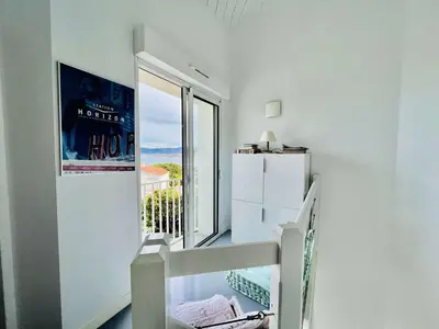 a white room with a staircase and a large window at Maison 4 pièces PIETROSELLA in Pietrosella