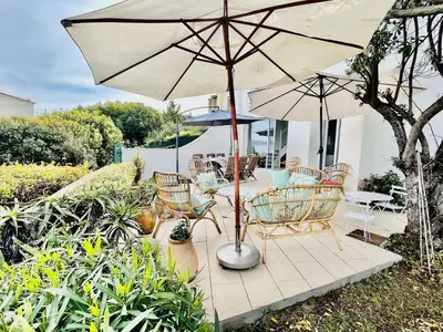 a patio with a table and chairs and an umbrella at Maison 4 pièces PIETROSELLA in Pietrosella