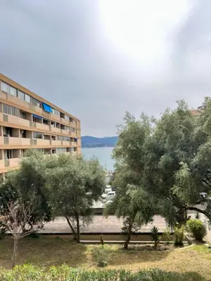 a building with trees in front of a body of water at T3 Ajaccio rte des Sanguinaires in Ajaccio