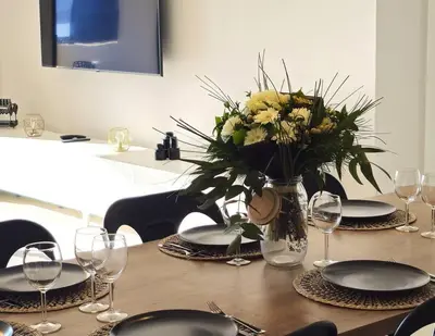 a table with plates and a vase of flowers on it at Nouveau Superbe appartement - Rsd Calypso Tiuccia in Casaglione