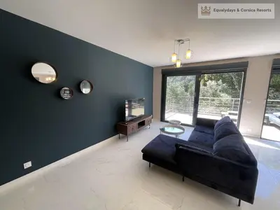 a living room with a black couch and a large window at Bonifacio Les Jardins secrets de Piale in Bonifacio