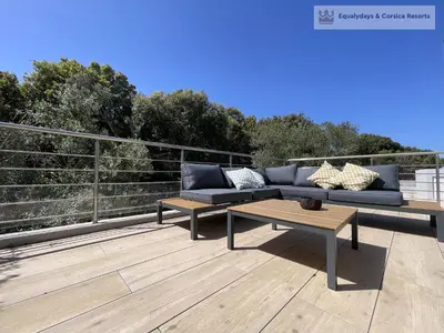 a patio with a couch and a table on a deck at Bonifacio Les Jardins secrets de Piale in Bonifacio