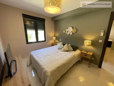 a bedroom with a bed and a window at Bonifacio Les Jardins secrets de Piale in Bonifacio