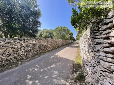 a stone wall next to a dirt road at Bonifacio Les Jardins secrets de Piale in Bonifacio