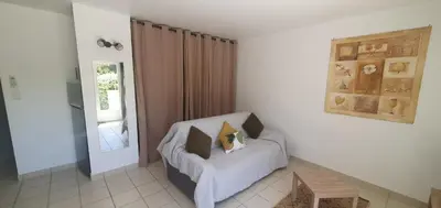 a living room with a chair and a table at Mini villa - T2 climatisé, proche des plages in Eccica-Suarella