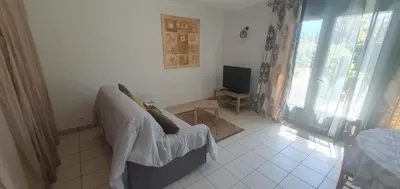 a living room with a couch and a television at Mini villa - T2 climatisé, proche des plages in Eccica-Suarella