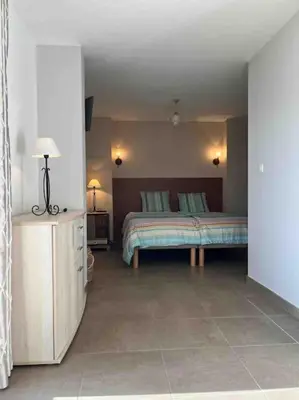 a bedroom with a bed and a table with a lamp at Studio 2 avec piscine & vue sur la baie d'Ajaccio in Alata