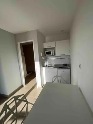 a kitchen with a table and two chairs in it at Studio 2 avec piscine & vue sur la baie d'Ajaccio in Alata