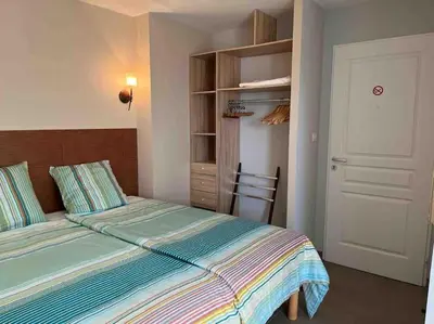 a small bedroom with a bed and a closet at Studio 2 avec piscine & vue sur la baie d'Ajaccio in Alata