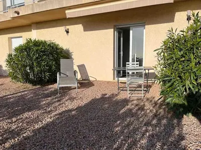 two chairs and a table in front of a building at Studio 2 avec piscine & vue sur la baie d'Ajaccio in Alata