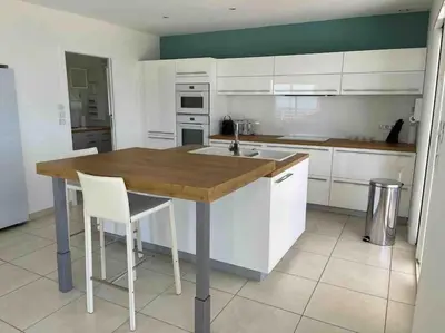 a kitchen with a wooden table and white cabinets at Casa Antonietta Alata vue imprenable sur la mer in Alata