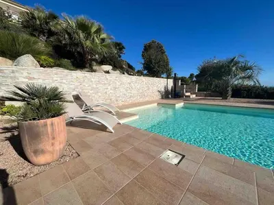 a swimming pool with a chair next to a wall at Casa Antonietta Alata vue imprenable sur la mer in Alata