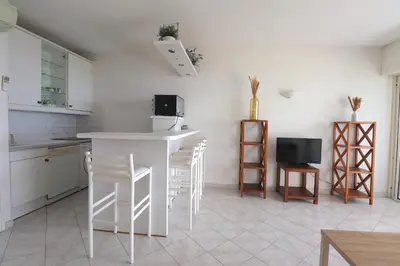 a white kitchen with a counter and a tv at T2 ARIA MARINA Route des Sanguinaires, Vue MER, Terrasse , Parking, Plage à 50M - 4pers in Ajaccio