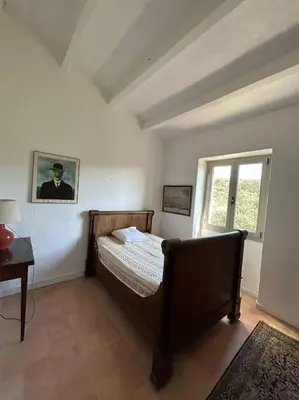 a bedroom with a bed and a table and a window at Château Balesi Bonifacio in Bonifacio