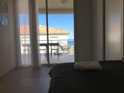 a bedroom with a bed and a view of a balcony at Appartement bord de mer T4 marina di bravonne N5-6 in Linguizzetta