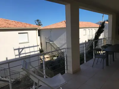 a balcony with chairs and a table and a staircase at Appartement bord de mer T4 marina di bravonne N5-6 in Linguizzetta