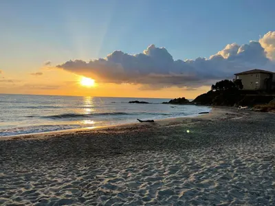 a sunset on a sandy beach with the ocean at Appartement bord de mer T4 marina di bravonne N5-6 in Linguizzetta