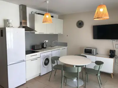 a kitchen with a table and a table and chairs at Appartement bord de mer T4 marina di bravonne N5-6 in Linguizzetta