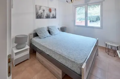 a bedroom with a bed with blue sheets and a window at Beau 3 pièces avec jardinet et cour, 5 min plages in Propriano