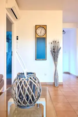 a room with a clock on the wall and a glass table at Beau 3 pièces avec jardinet et cour, 5 min plages in Propriano