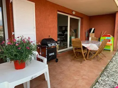 a living room with a table and chairs and a stove at Beau 3 pièces avec jardinet et cour, 5 min plages in Propriano
