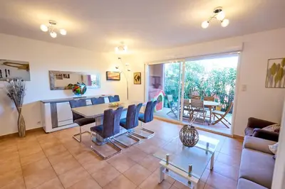 a living room with a table and chairs at Beau 3 pièces avec jardinet et cour, 5 min plages in Propriano