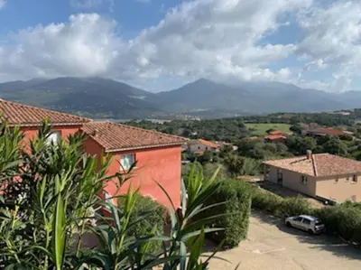 a view of a house with mountains in the background at Beau 3 pièces avec jardinet et cour, 5 min plages in Propriano