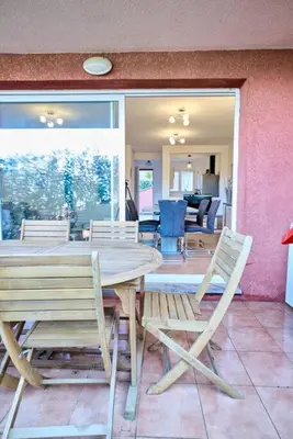 a wooden table and chairs in a room at Beau 3 pièces avec jardinet et cour, 5 min plages in Propriano