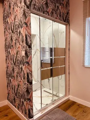 a glass shower in a room with a floral wallpaper at Appartement au centre du Port de Bonifacio in Bonifacio
