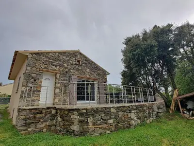 a stone house with a balcony on a field at A Casetta in Prunelli-di-Fiumorbo