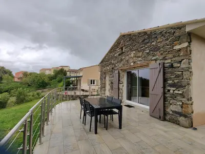 a stone building with a table and chairs on a patio at A Casetta in Prunelli-di-Fiumorbo