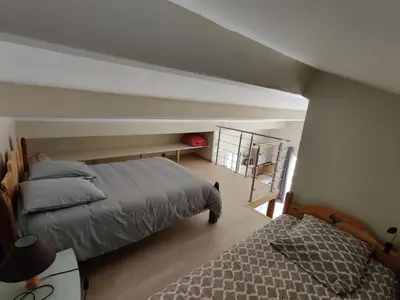 an attic bedroom with two beds and a ladder at A Casetta in Prunelli-di-Fiumorbo