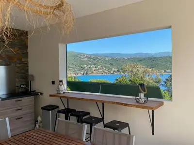 a kitchen with a large window with a table and chairs at A Pineta Corsa in Pietrosella