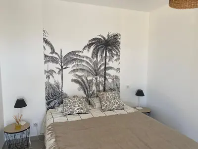 a bedroom with a bed with palm trees mural on the wall at A Pineta Corsa in Pietrosella