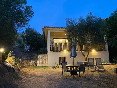 a table and chairs with an umbrella in front of a house at Villa 4 personnes - 2 chambres - Figari in Figari