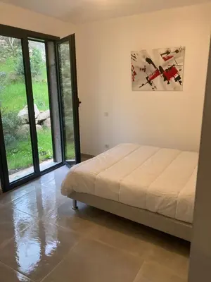 a bedroom with a bed and sliding glass doors at Villa 4 personnes - 2 chambres - Figari in Figari
