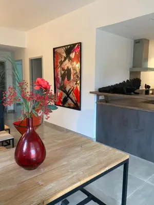 a red vase with flowers on a table in a kitchen at Villa 4 personnes - 2 chambres - Figari in Figari